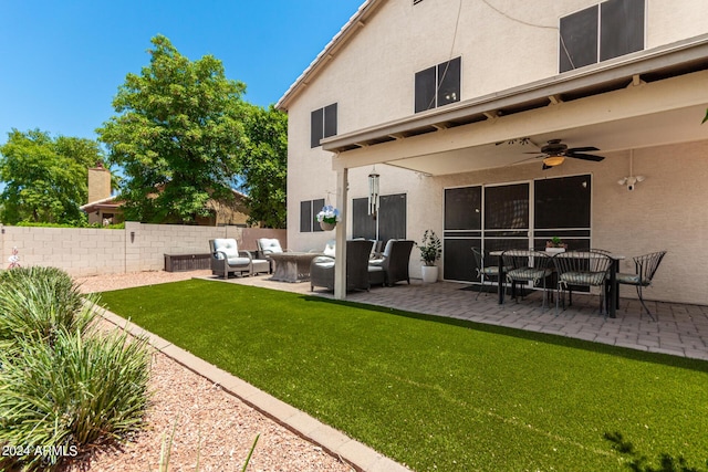 back of property with ceiling fan, an outdoor living space, a patio, and a lawn