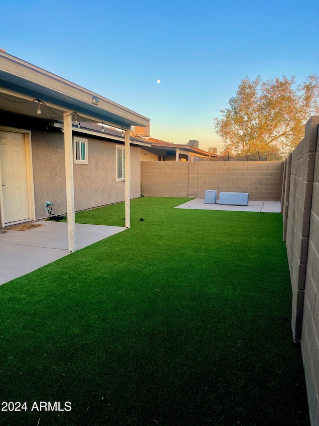 yard at dusk with an outdoor living space and a patio