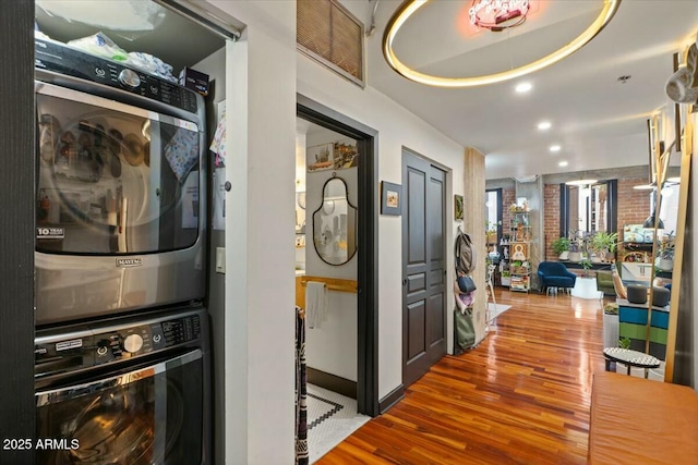 hallway featuring wood-type flooring and stacked washer / drying machine