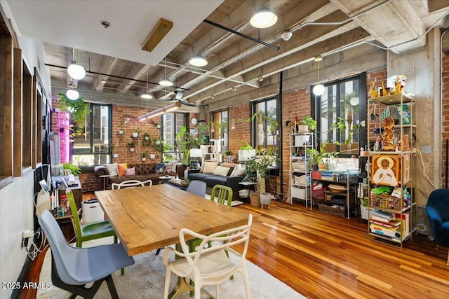 dining room with brick wall, hardwood / wood-style floors, and a healthy amount of sunlight