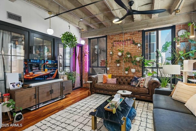 living room featuring wood-type flooring, plenty of natural light, and brick wall