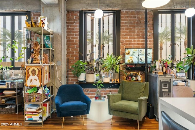 sitting room featuring brick wall and hardwood / wood-style floors