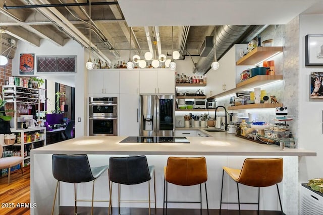 kitchen with white cabinets, stainless steel appliances, sink, kitchen peninsula, and a breakfast bar area