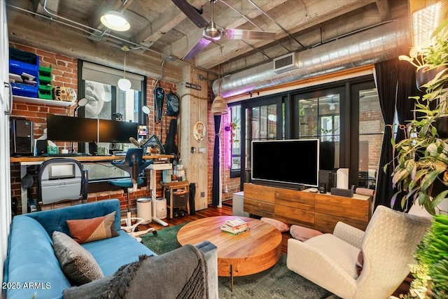 living room with hardwood / wood-style flooring and brick wall