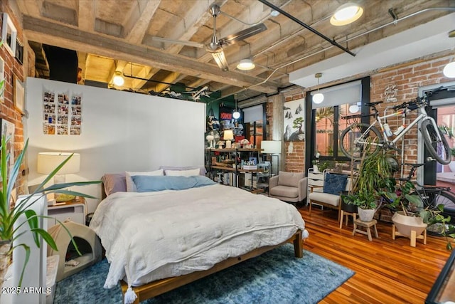 bedroom featuring brick wall and hardwood / wood-style floors