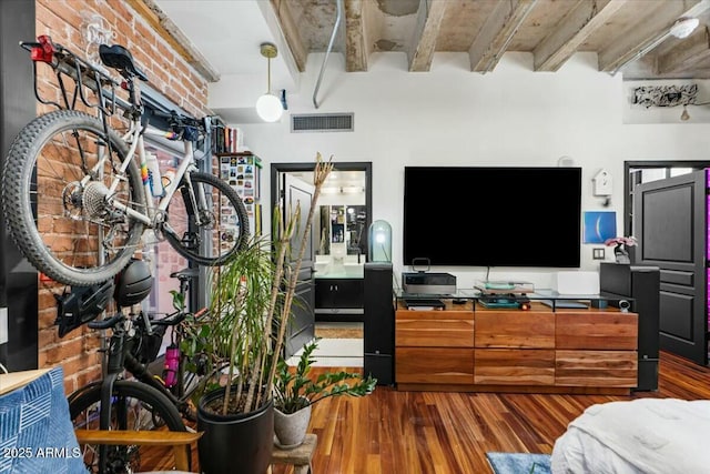 bedroom with hardwood / wood-style floors, beam ceiling, and brick wall