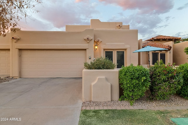 pueblo revival-style home featuring a garage