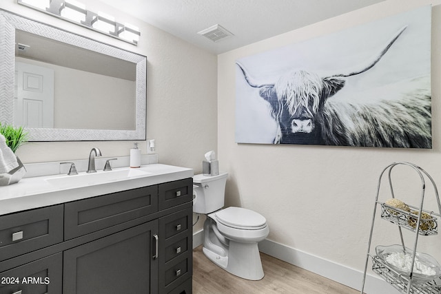 bathroom featuring hardwood / wood-style flooring, vanity, toilet, and a textured ceiling