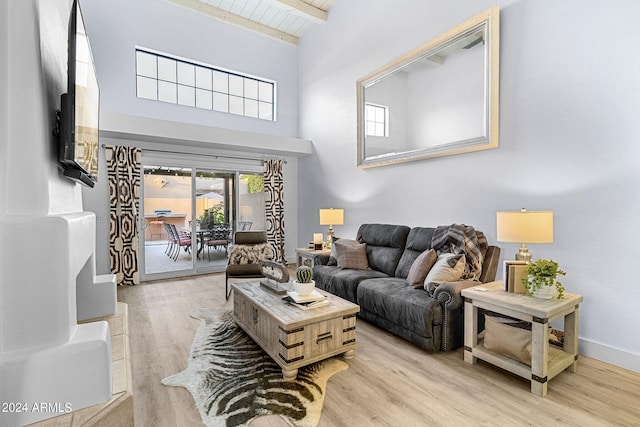 living room featuring beamed ceiling and light hardwood / wood-style floors