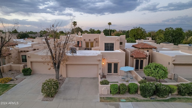 pueblo revival-style home featuring french doors and a garage