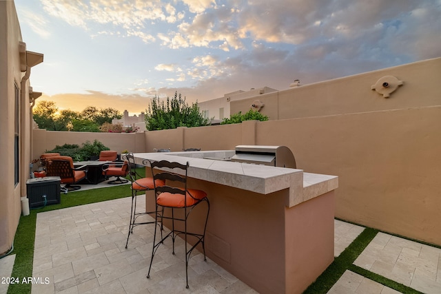 patio terrace at dusk featuring an outdoor bar