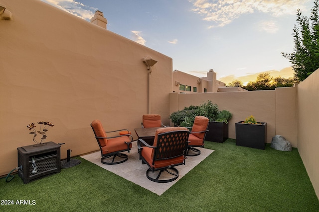 patio terrace at dusk featuring a lawn