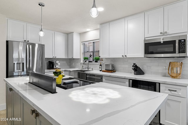 kitchen featuring white cabinets, stainless steel appliances, and hanging light fixtures