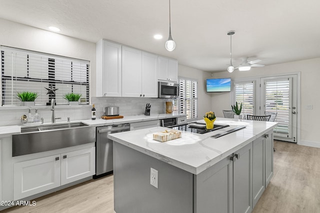 kitchen with stainless steel appliances, ceiling fan, decorative light fixtures, a center island, and white cabinetry