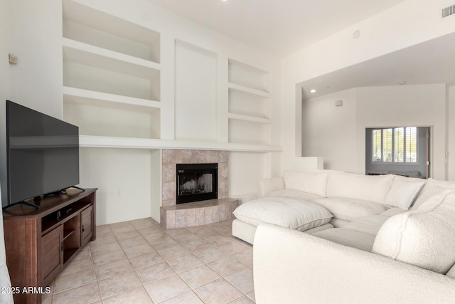 tiled living room featuring a tile fireplace and built in features