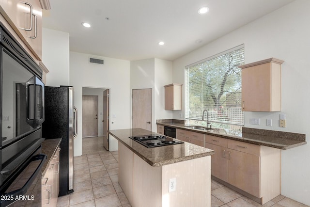 kitchen with a center island, light brown cabinets, black appliances, sink, and light tile patterned floors