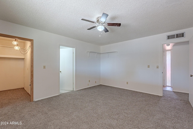 unfurnished bedroom with carpet floors, a spacious closet, a closet, and ceiling fan