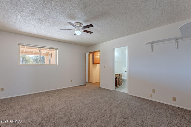 unfurnished bedroom with a textured ceiling, light colored carpet, ensuite bath, and ceiling fan