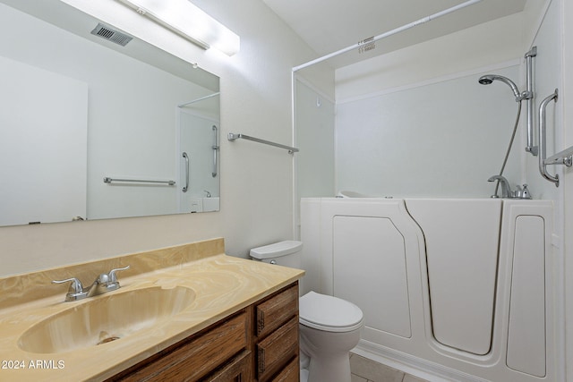 bathroom with tile patterned floors, a tub to relax in, vanity, and toilet