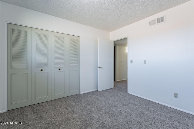 unfurnished bedroom with a closet, dark carpet, and a textured ceiling