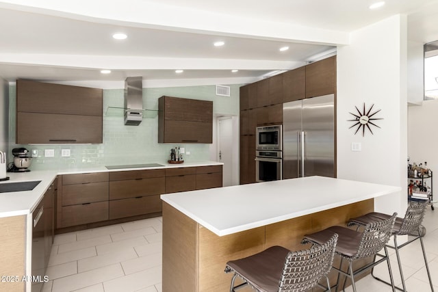 kitchen featuring wall chimney exhaust hood, modern cabinets, and built in appliances