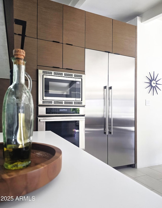 kitchen featuring modern cabinets, tile patterned floors, built in appliances, and light countertops