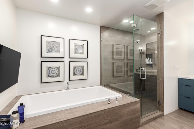 full bath with visible vents, a garden tub, a shower stall, and wood finished floors