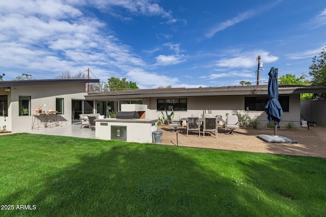 rear view of property featuring a lawn, stucco siding, and an outdoor kitchen