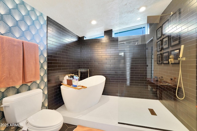 bathroom featuring a textured ceiling, separate shower and tub, toilet, and tile walls