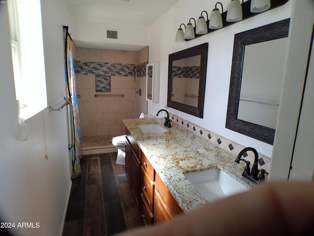 bathroom featuring tiled shower, vanity, and toilet