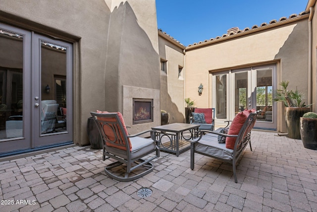 view of patio with french doors and an outdoor fireplace