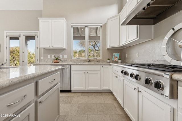 kitchen with range hood, sink, white cabinets, stainless steel appliances, and light stone countertops