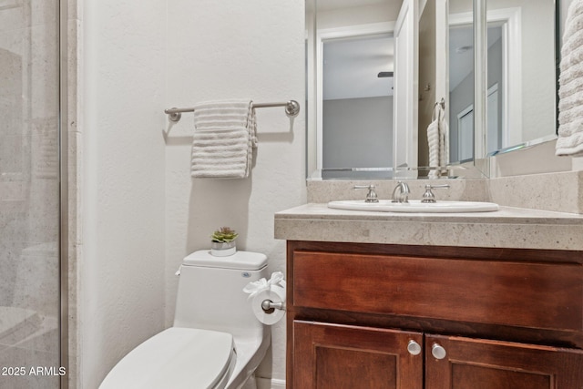 bathroom with vanity, a shower with shower door, and toilet