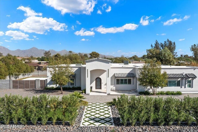 view of front of house featuring a mountain view, stucco siding, and fence