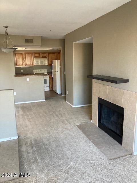 unfurnished living room with a tile fireplace and light carpet