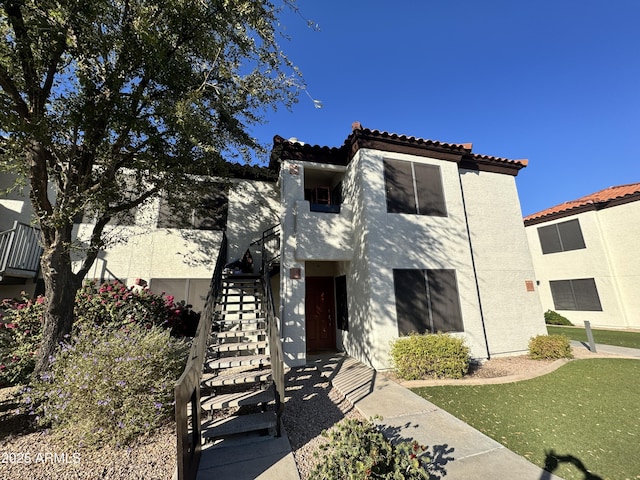 view of front of house with stairs, a tiled roof, and stucco siding