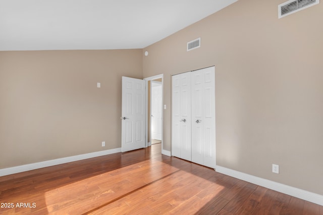 unfurnished bedroom featuring baseboards, a closet, wood finished floors, and visible vents