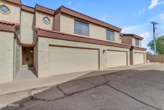 townhome / multi-family property with a tile roof and stucco siding