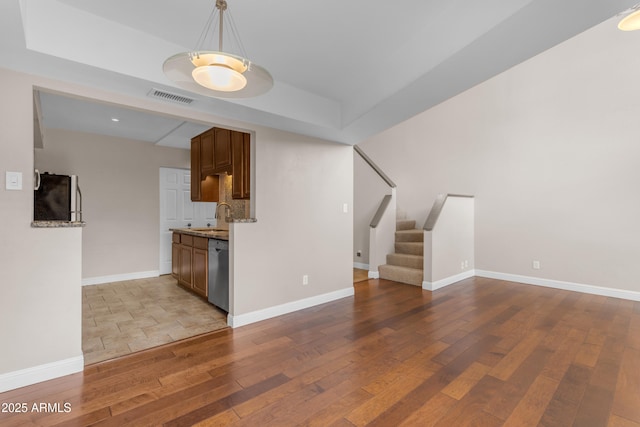 interior space featuring appliances with stainless steel finishes, a sink, wood-type flooring, baseboards, and visible vents