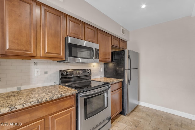kitchen with backsplash, light stone countertops, brown cabinets, baseboards, and stainless steel appliances