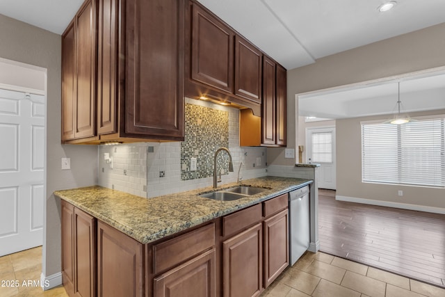 kitchen with light stone countertops, dishwasher, baseboards, a sink, and backsplash