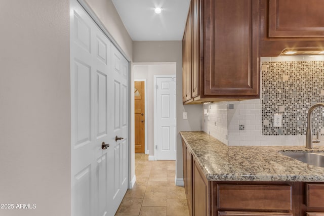 kitchen with light stone counters, a sink, and tasteful backsplash