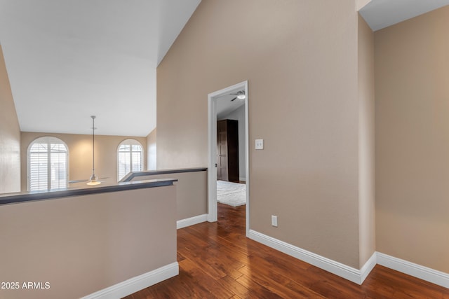 unfurnished room with ceiling fan, baseboards, and dark wood-type flooring