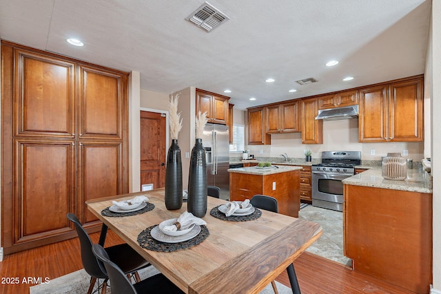 kitchen featuring appliances with stainless steel finishes, a kitchen island, visible vents, and under cabinet range hood