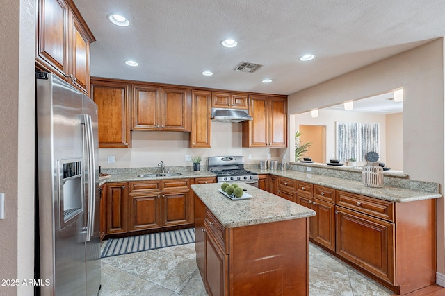 kitchen featuring visible vents, appliances with stainless steel finishes, a sink, a peninsula, and under cabinet range hood