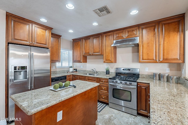 kitchen featuring visible vents, appliances with stainless steel finishes, light stone counters, under cabinet range hood, and a sink