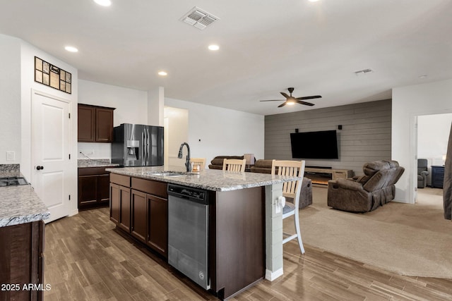 4595 W Foldwing Dr, San Tan Valley, AZ 85144 - kitchen with appliances with stainless steel finishes, a sink, a kitchen bar, dark brown cabinetry, and wood finished floors