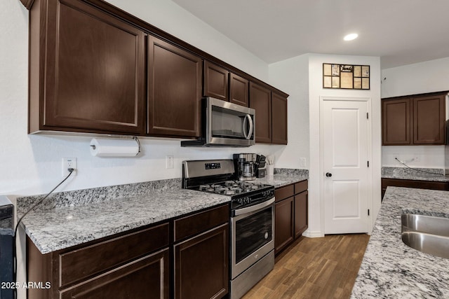 4595 W Foldwing Dr, San Tan Valley, AZ 85144 - kitchen featuring stainless steel appliances, dark brown cabinetry, dark wood-style flooring, light stone counters, and recessed lighting