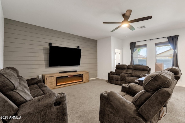 4595 W Foldwing Dr, San Tan Valley, AZ 85144 - living room with carpet floors, a ceiling fan, wood walls, a glass covered fireplace, and baseboards