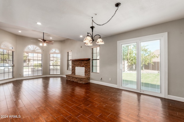 unfurnished living room with dark hardwood / wood-style floors, ceiling fan with notable chandelier, and a fireplace